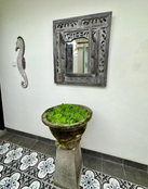 Ornately carved wood wall mirror displayed above a decorative stone planter.