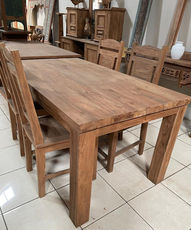 Rectangular solid teak dining table with matching high-back wooden chairs.