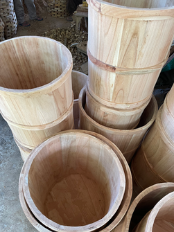 Close-up view of unfinished wooden barrel planters showing their natural wood interiors and banded construction.
