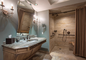 Luxury walk-in shower and custom double vanity with carved wood cabinetry.