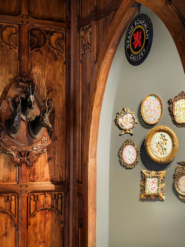Custom carved wood doorway and wall décor in a rustic hallway featuring Balinese-inspired teak woodwork.