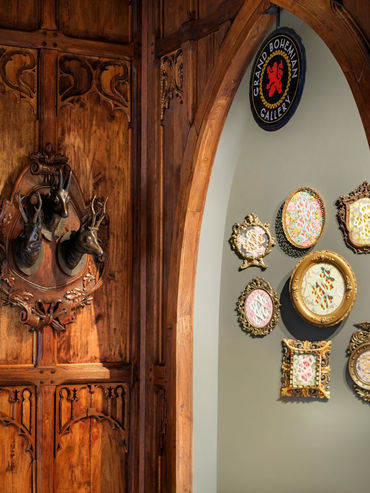 Custom carved wood doorway and wall décor in a rustic hallway featuring Balinese-inspired teak woodwork.