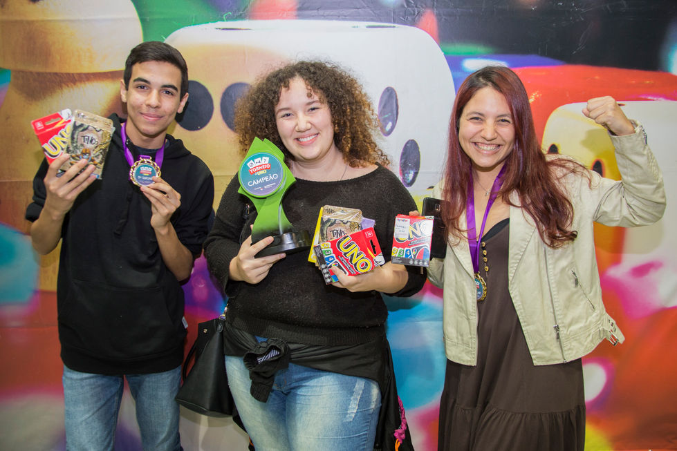 3 campeões do torneio de uno posam para a foto sorrindo.