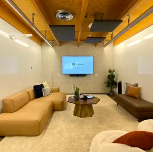 Modern lounge with couches, TV, and wooden ceiling.