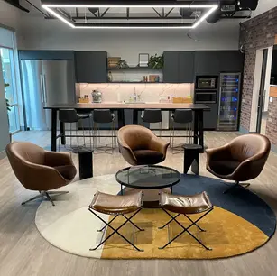 Modern lounge with chairs, round rug, and kitchen area.