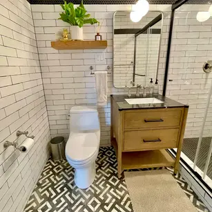 Modern bathroom with geometric floor tiles and wooden accents.