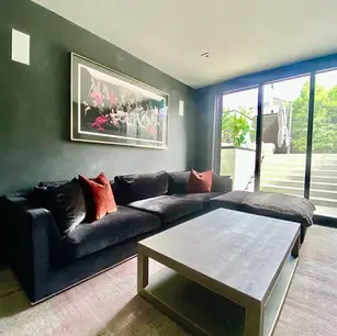 Modern living room with dark sofa and large artwork.