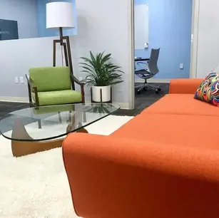 Modern office lounge with colorful furniture and glass table.