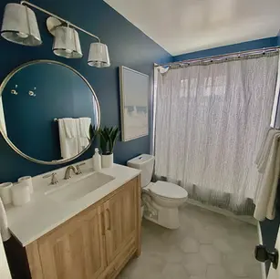 Modern bathroom with blue walls and wooden vanity.