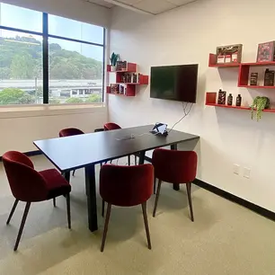 Modern meeting room with red chairs and wall shelves.