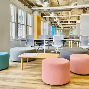 Modern office space with colorful seating and desks.