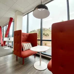 Modern office lounge with red seating and large windows.