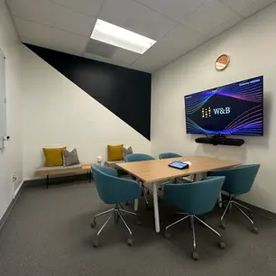 Modern conference room with table, chairs, and screen.