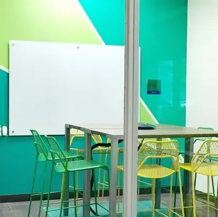 Modern meeting room with colorful chairs and geometric wall.