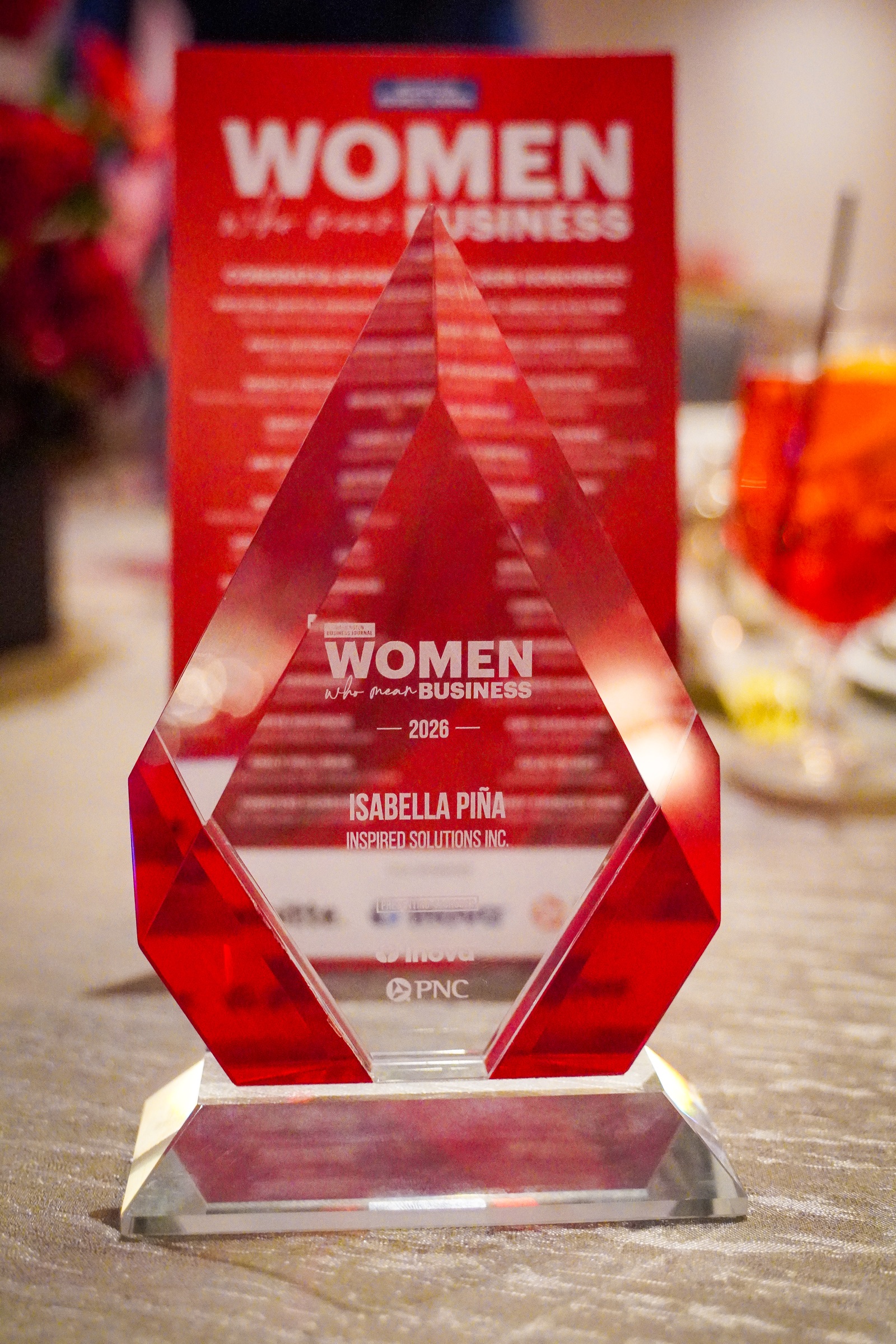 Close-up of Isabella Piña's red 2026 Washington Business Journal Women Who Mean Business award.