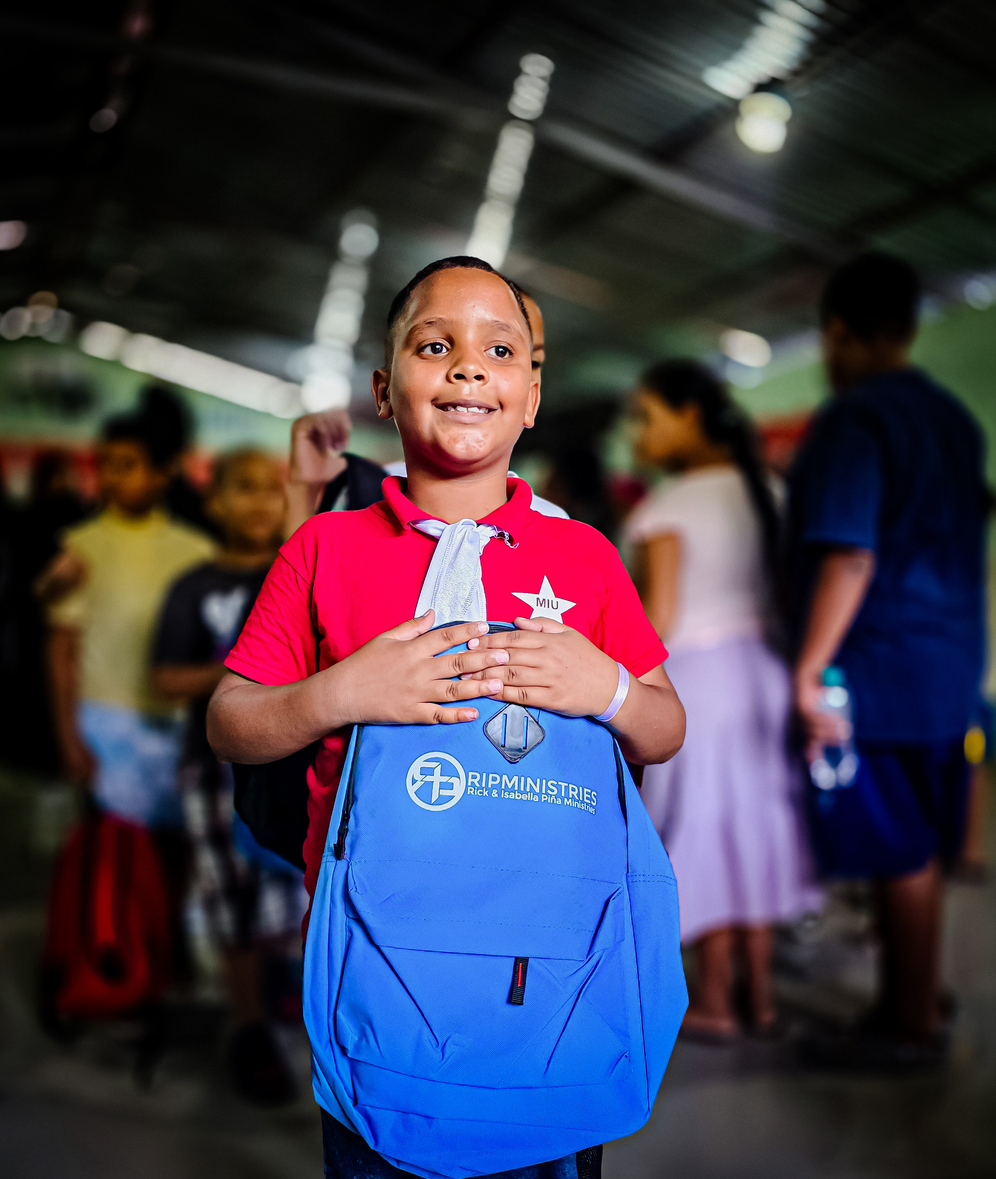 A boy holds his new Rick and Isabella Pina Ministries backpack during the 2026 distribution in the Dominican Republic
