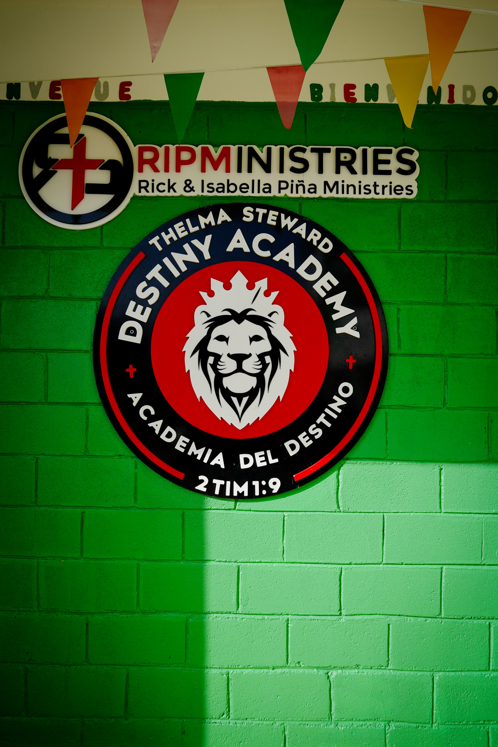The Thelma Steward Destiny Academy crest painted on a green wall with the verse 2 Timothy 1:9