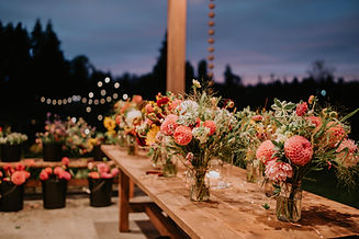 A workshop table with arrangements made by guests from buckets of bulk, seasonal flowers.