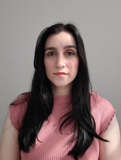 Mulher de 30 anos branca, olhos castanhos e cabelo castanho com comprimento médio com camiseta de manga de cor rosa olhando para quem está tirando a foto