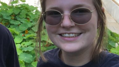 Amy wearing sunglasses smiling in front of her aquaponics farm