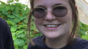 Amy wearing sunglasses smiling in front of her aquaponics farm