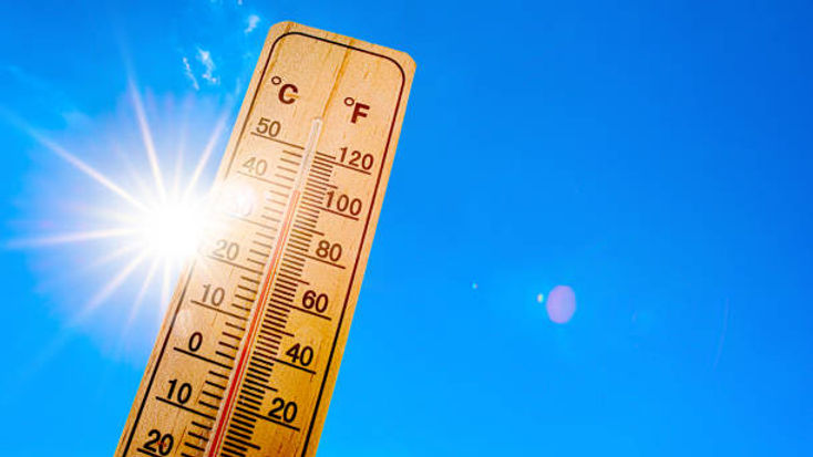Image is a close up of a thermometer showing the temperature at 100 degrees Fahrenheit and the sun is shining behind the thermometer