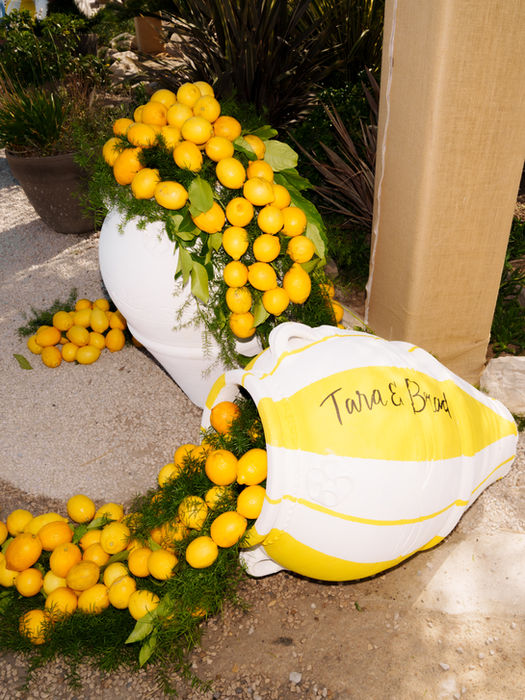 Lemons spilling from a white vase and a striped bag labeled TARA & BRAD