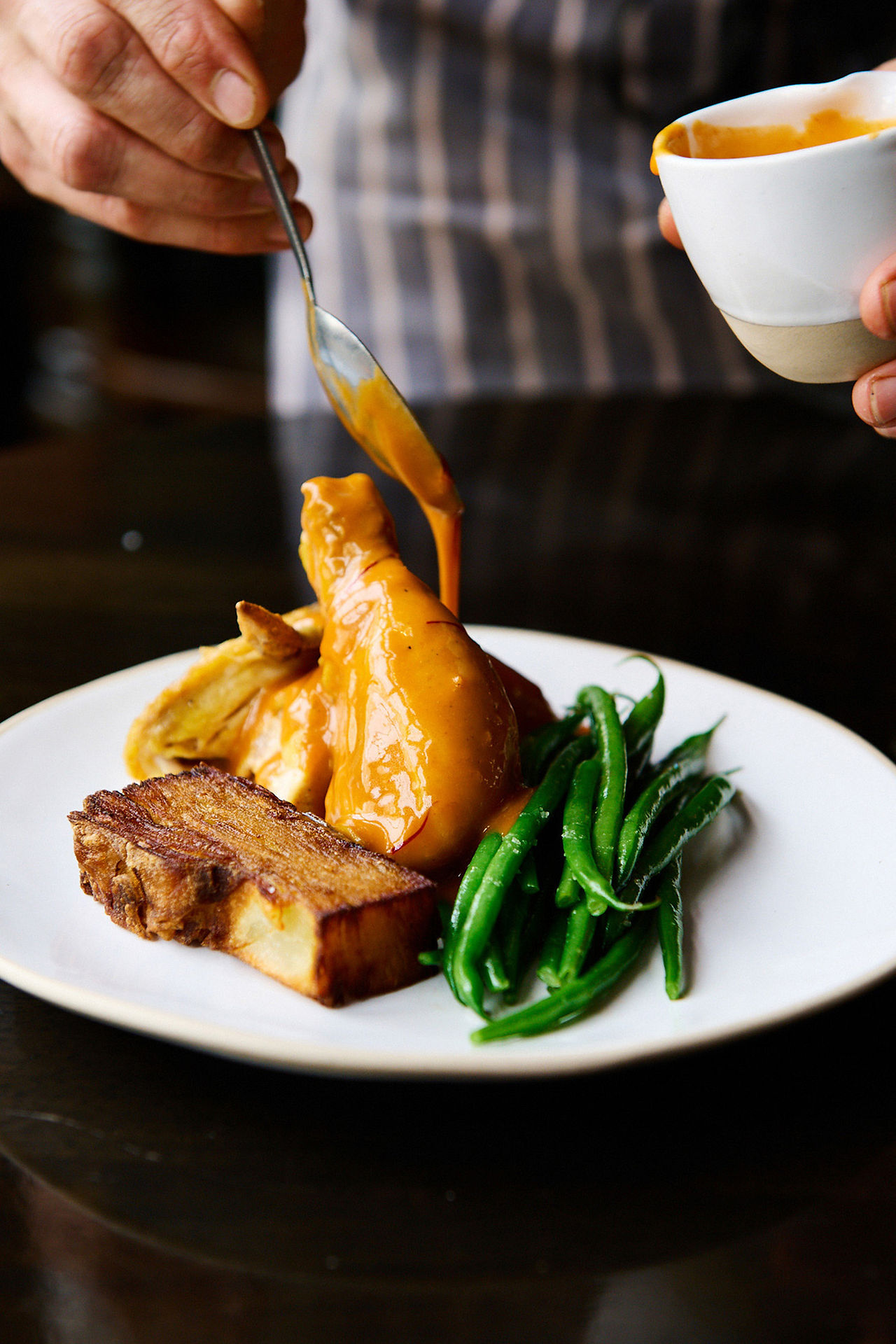 autumn menu photography Sussex restaurants, pouring sauce over a chicken dish with green beans.