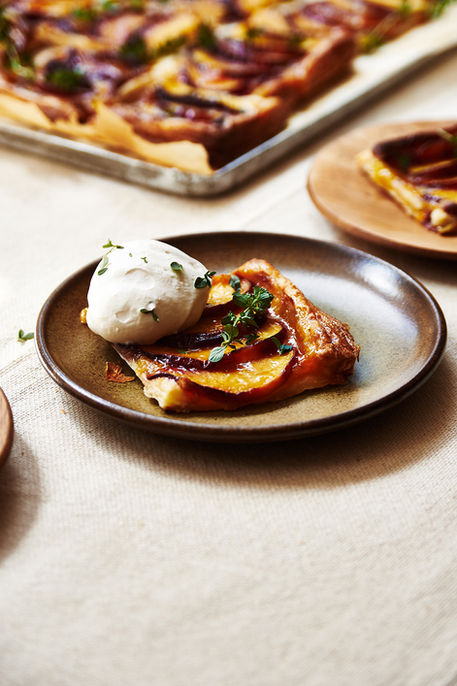 A slice of vegan peach frangipane tart on a small ceramic tea plate.