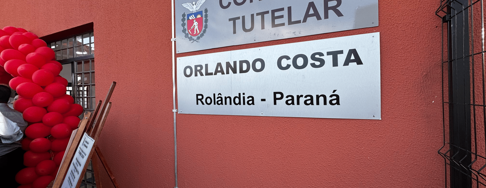 Parede de fora da sede do Conselho Tutelar, com duas placas em cinza, indicando que essa é a sede do Conselho Tutelar - Orlando Costa, Rolândia no Paraná.