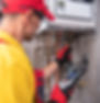 Technician in red cap inspecting a boiler with a diagnostic tool.