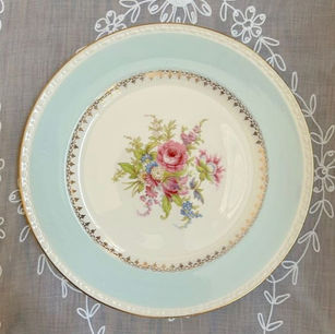 Vintage floral dinner plate with a thick light blue border and gold rim along with a floral design in the center of the plate.