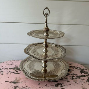 a three-tier silver tray with intricate design upon a table