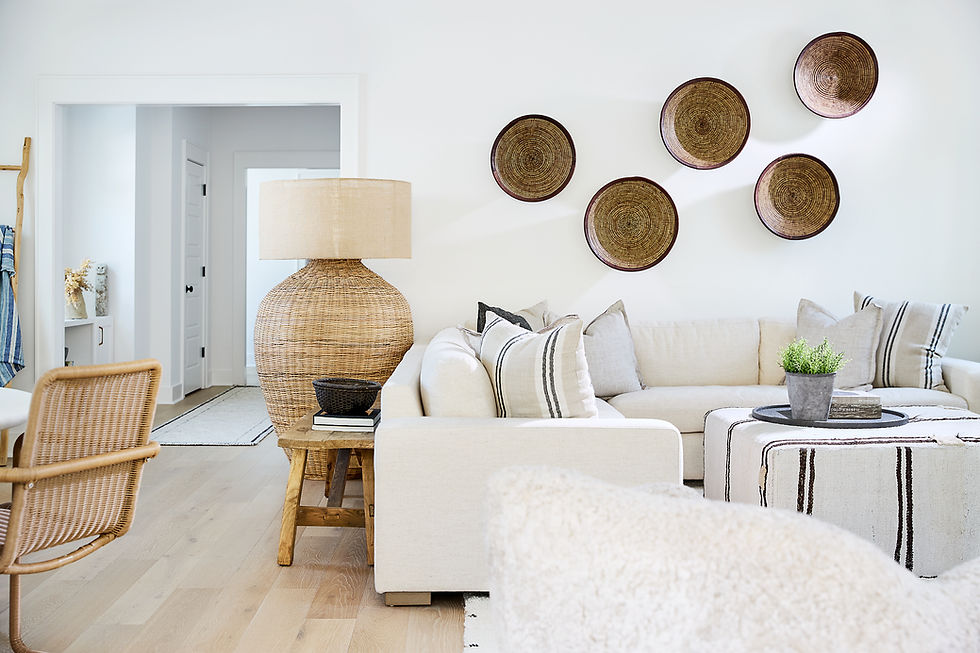 Bright neutral living room with cream sofa, woven lamp, rattan chair, and wall baskets in a calm, airy setting