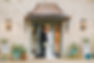 Bride and Groom touching foreheads standing in doorway of historic Stonehouse Villa limestone building with succulents on either side of front door. Photographer: Two Pair