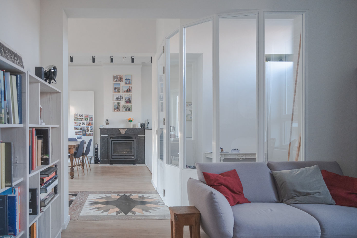 Salon lumineux avec cloison vitrée et vue vers la salle à manger et la cheminée