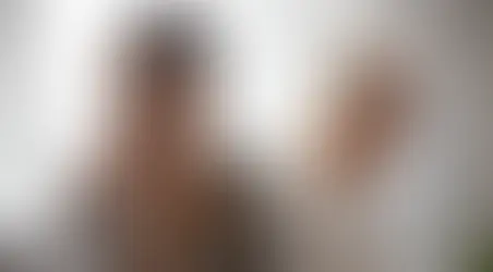 Two women sit back-to-back indoors, one younger with a pensive expression, the other older looking away, representing the emotional gap in parent-child estrangement.