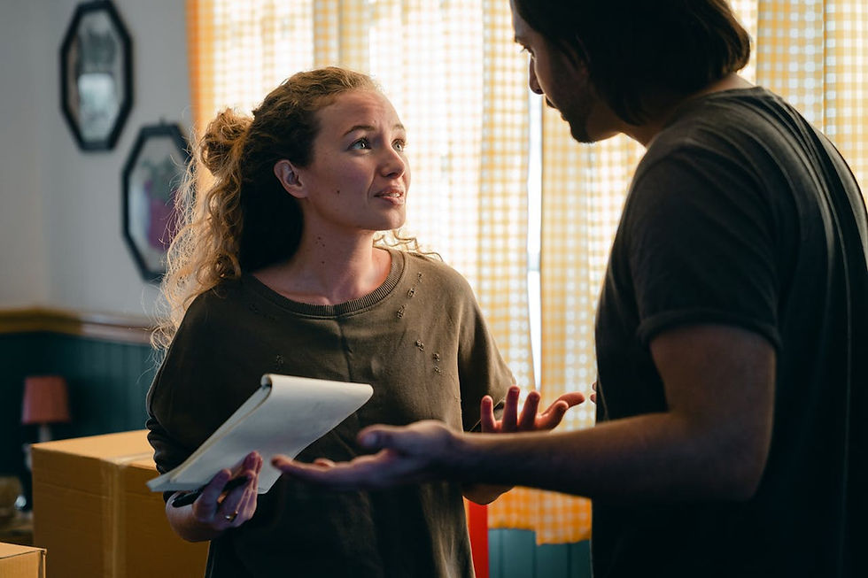 A couple standing together reviewing a budget with financial power struggles.