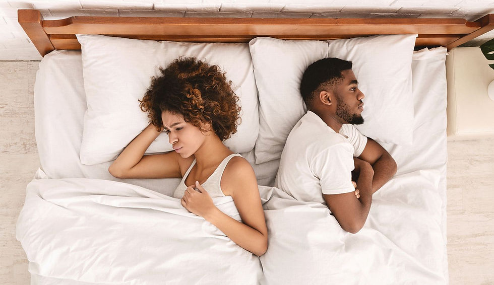 couple sitting apart on a bed looking disapointed and disconnected, illustrating intimacy challenges and mismatched sexual desire in a relationship.