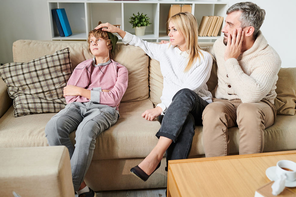 a man and woman sit on a couch with their child who is looking away representing distance and pulling away from the parents.