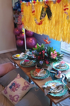 Picnic inspirado en Hawái y Stitch lleno de flores hawaianas, hojas tropicales y faldas de hierba.