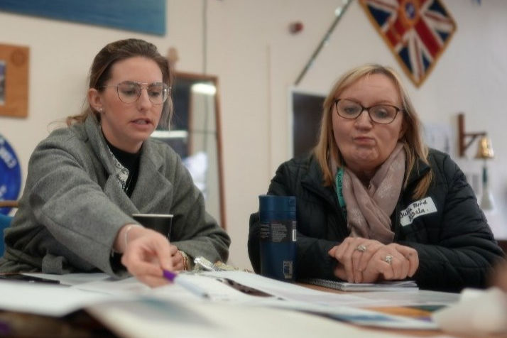 Laura, Director of Healthbox and member of the Koala North West team planning the thriving families project in a school hall. They are discussing healthbox supporting the project with children's counselling support