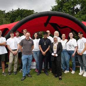 lord mayor of chester standing with simon sandford director of healthbox and 10 bank of america volunteers with white t-shirts on. They are stood in front of healthbox's big red tent in the park