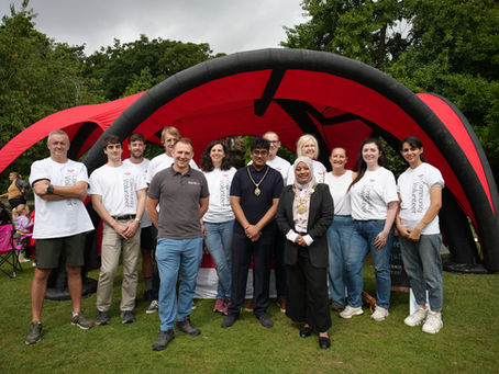 lord mayor of chester standing with simon sandford director of healthbox and 10 bank of america volunteers with white t-shirts on. They are stood in front of healthbox's big red tent in the park