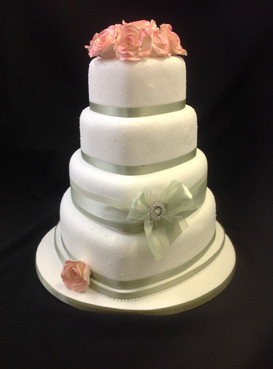 a multi tier white and silver cake with pink flowers decorating it