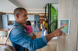 man holding his child whilst activating his security system with a lady and child in the b