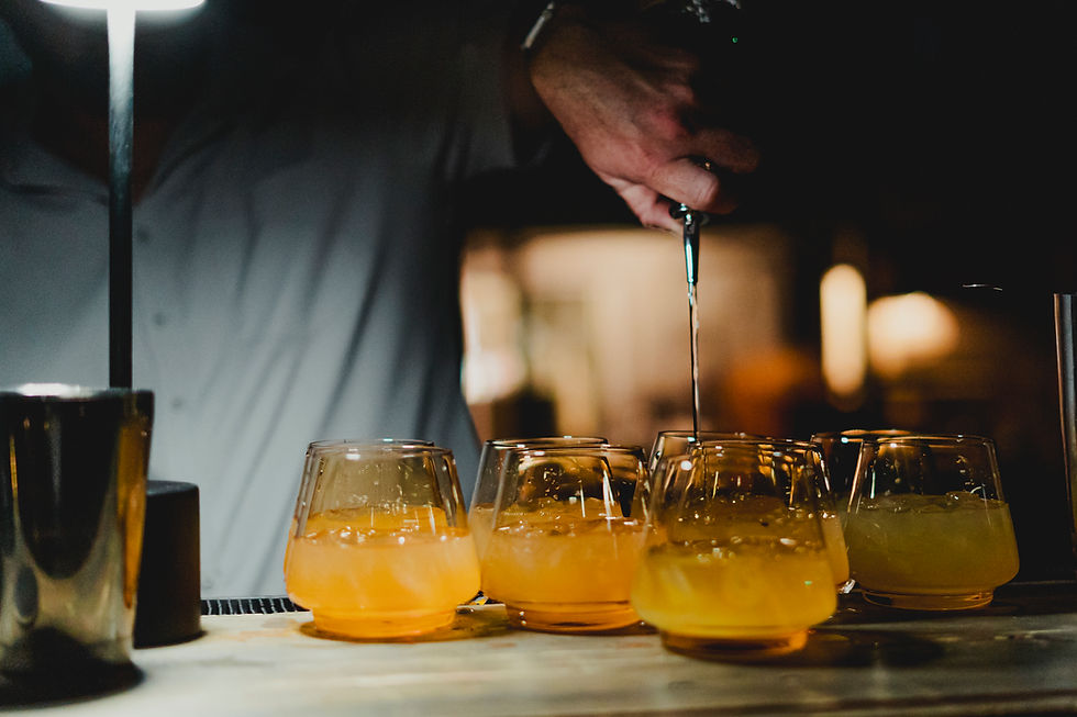Bartender pouring drinks into glowing amber cocktails