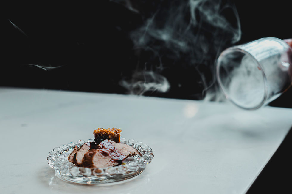 Architectural plated meat dish under smoke on a crystal plate