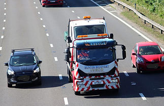 Hunter Recovery truck on the road with van on the back