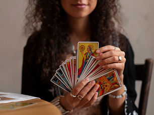 A hand holding a custom playing card deck with personalized artwork, surrounded by packaging and printing tools.